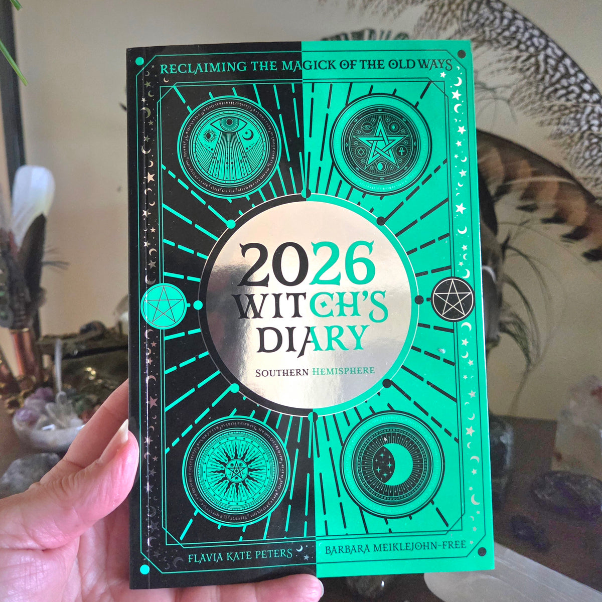 Green and black book titled '2026 Witch's Diary' held by a hand.