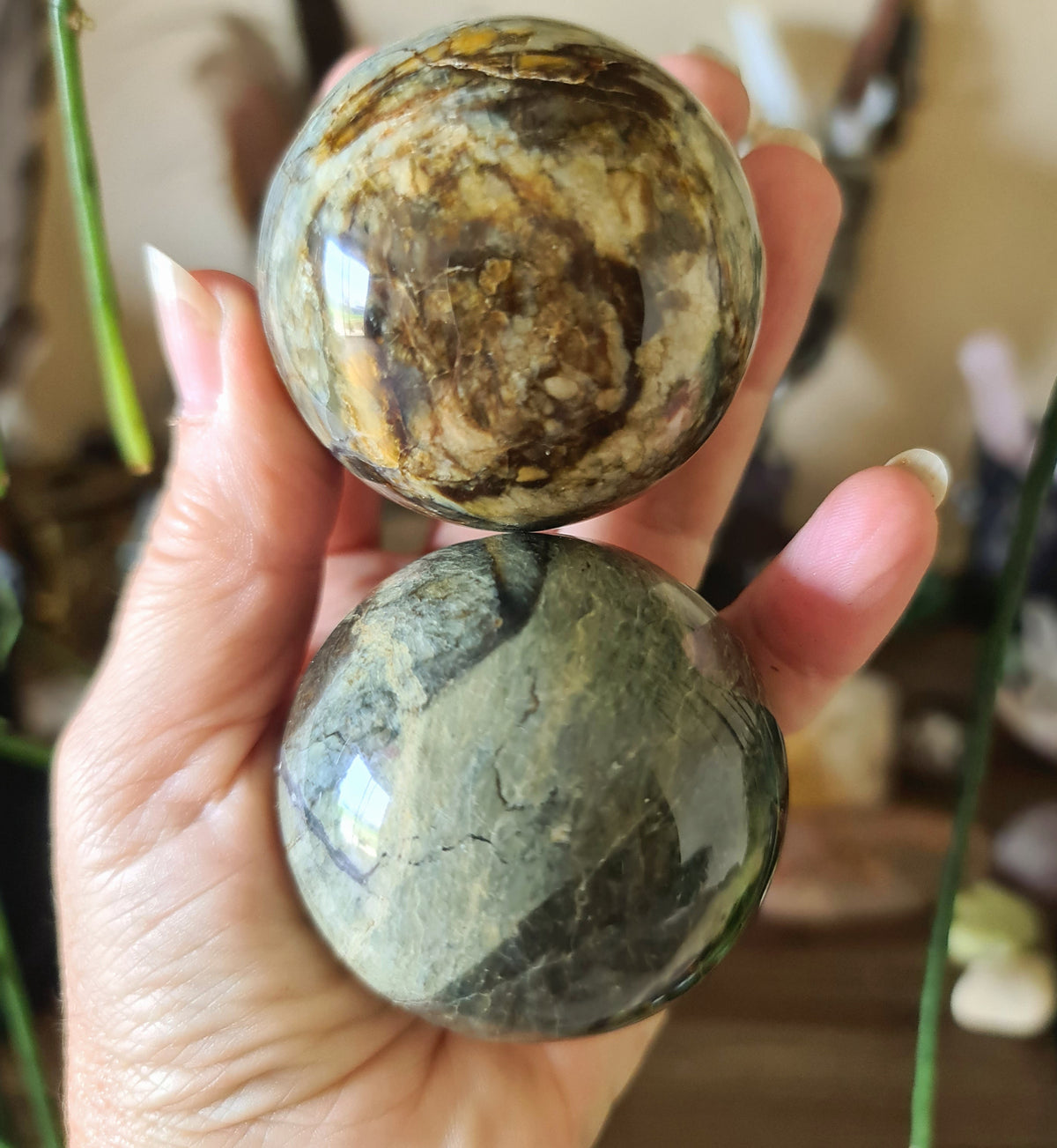 Two polished spherical stones with a swirled blue and dark patch design, held in a person's hand.
