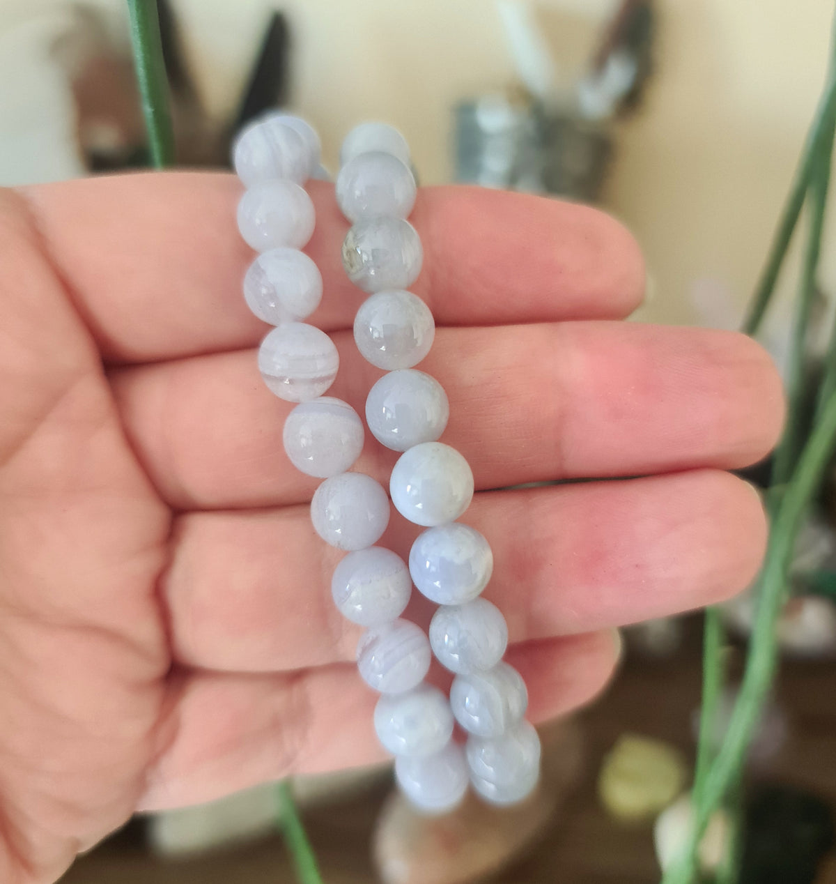 A person holding a bracelet with blue lace agate beads.
