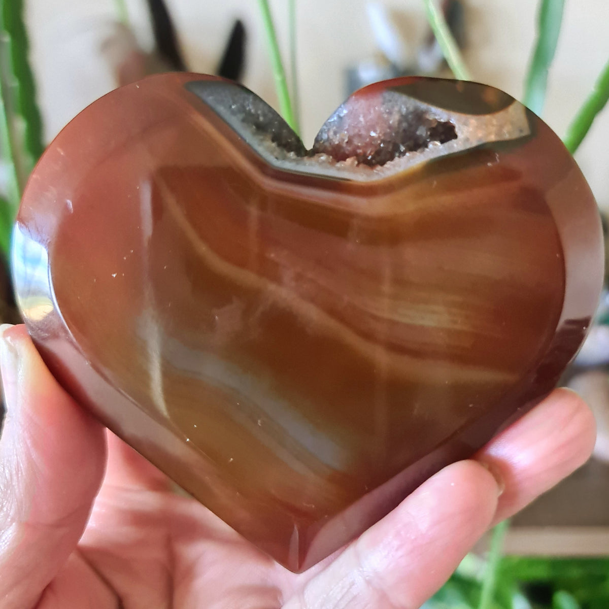 A person holding a large red Carnelian heart-shaped stone