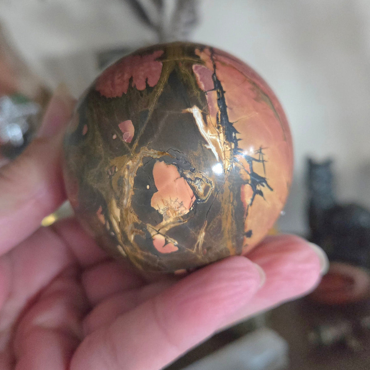 Polished stone with a marbled pattern held in a hand against a blurred background
