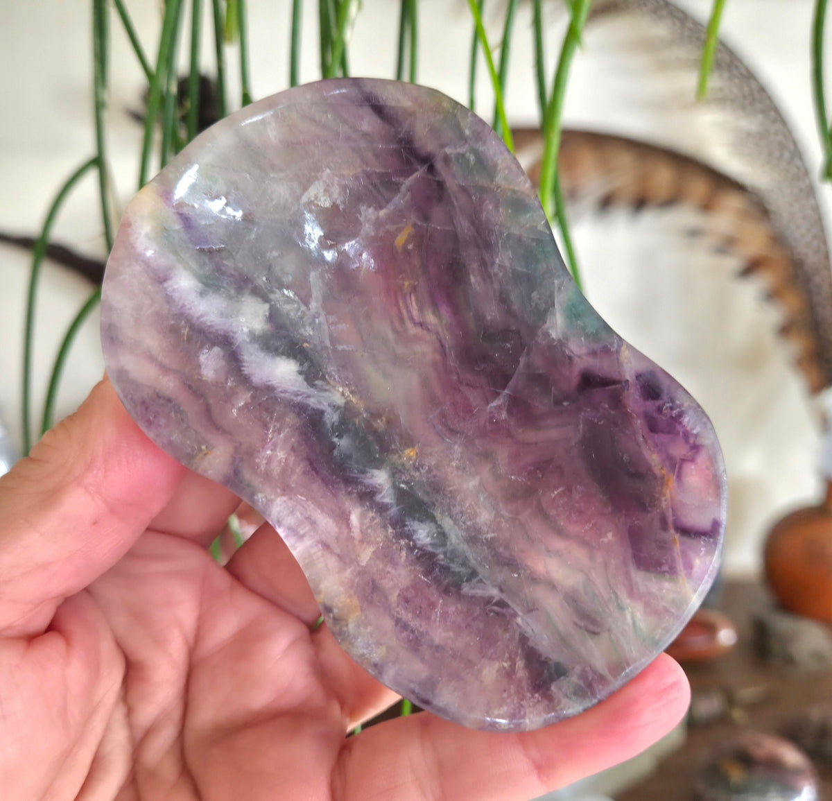 Hand holding a polished amethyst crystal with a blurred background