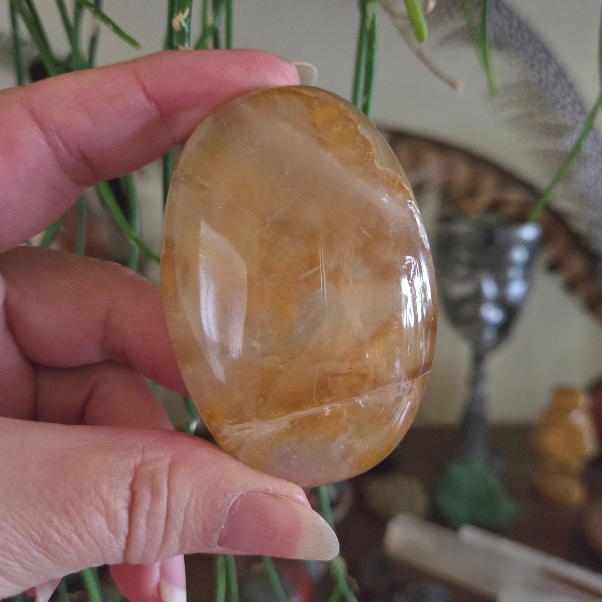 Hand holding a polished stone with a blurred indoor background