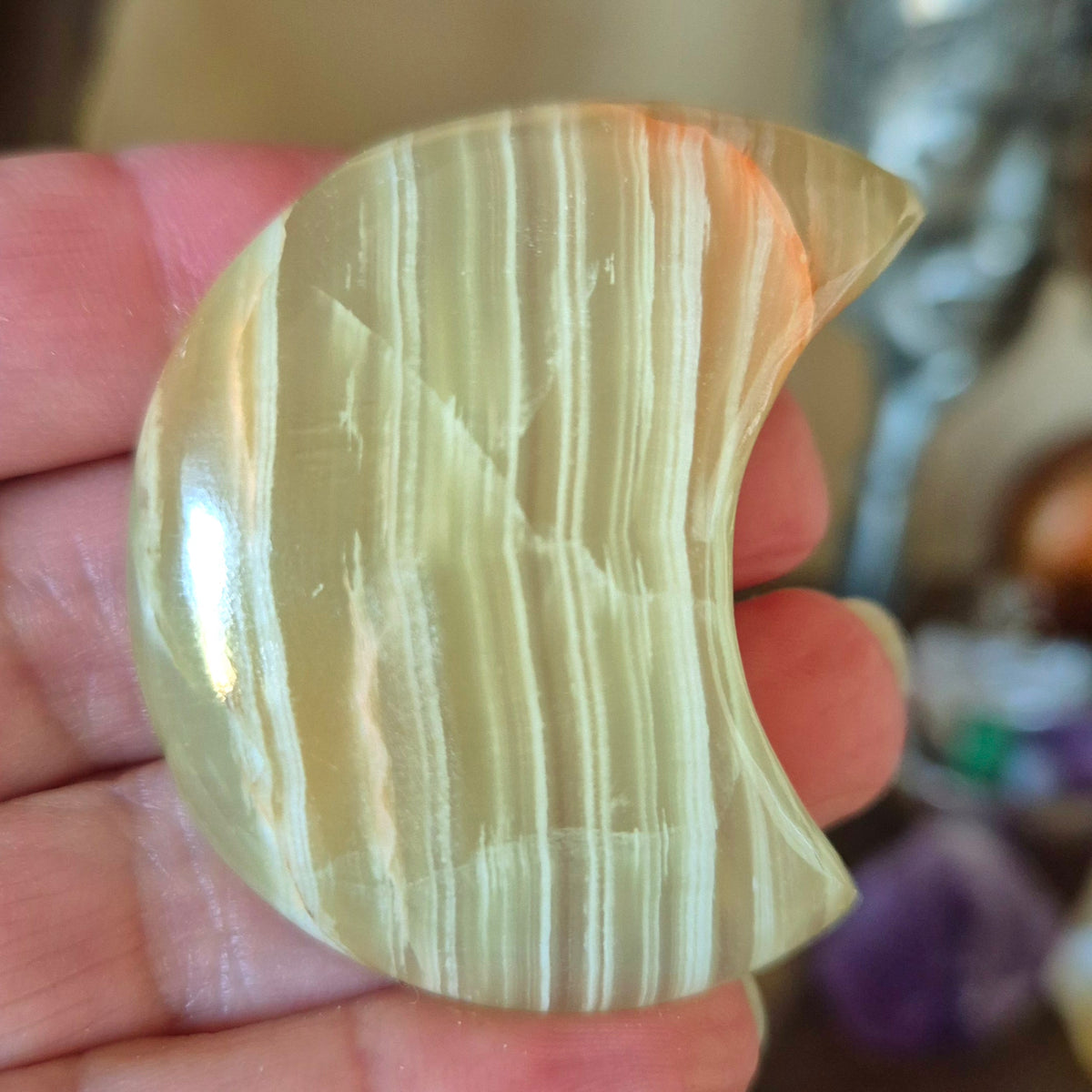 A polished green onyx moonstone held in a person's hand.