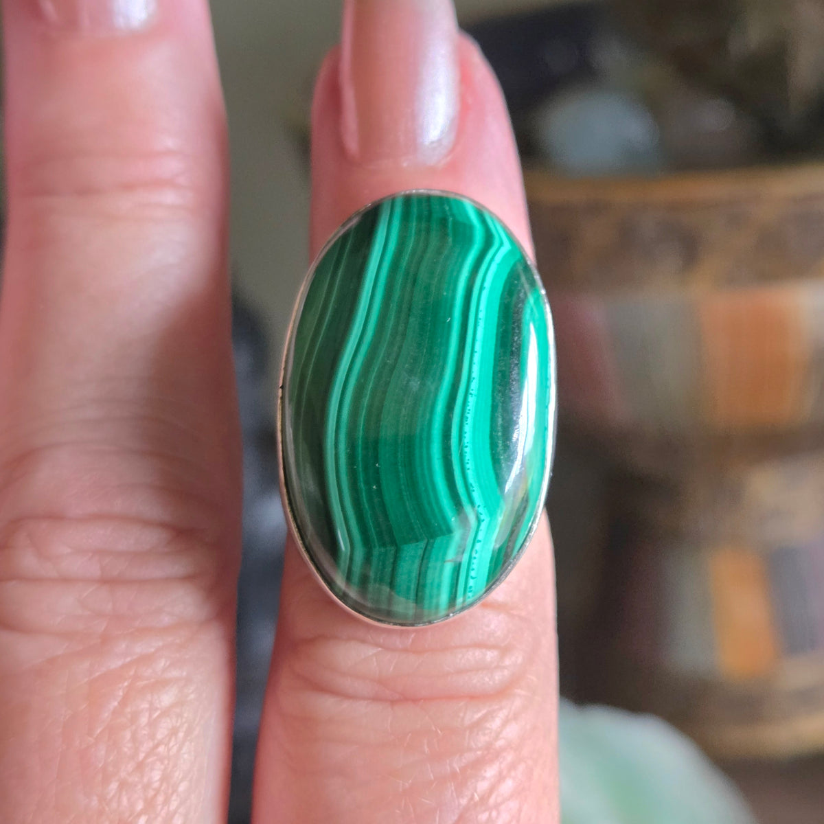 Green malachite ring on a finger with a blurred background