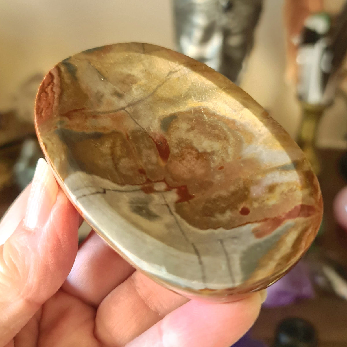 A polished stoneware bowl with a marbled multicolor design, held in a person's hand.