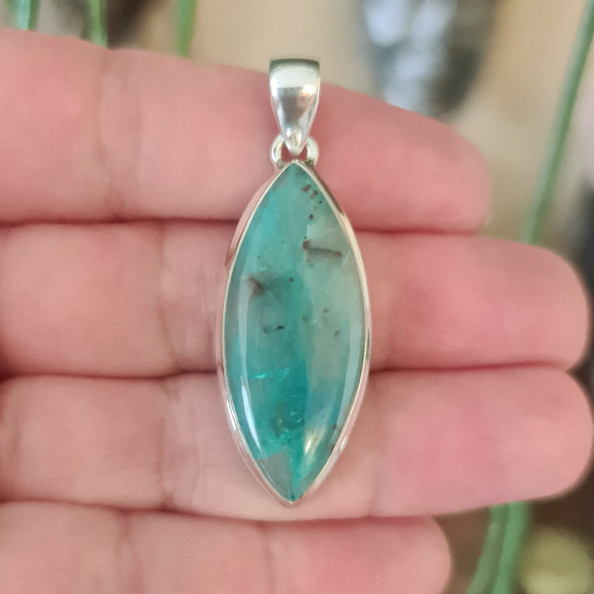 blue elongated crystal pendant held in a hand