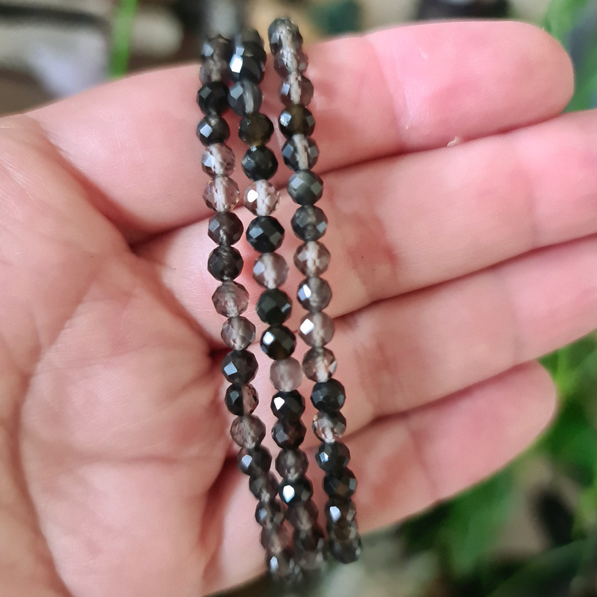 smoky quartz faceted bead bracelet held in a hand