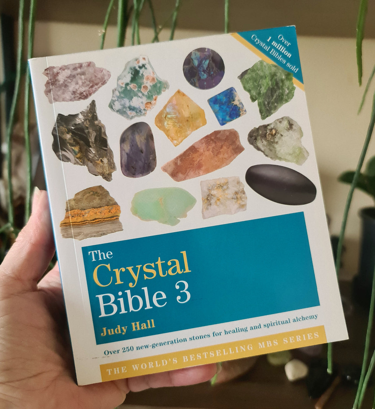 The cover of the book 'The Crystal Bible 3' by Judy Hall, featuring an array of colorful crystals and a central photograph of a smiling woman.