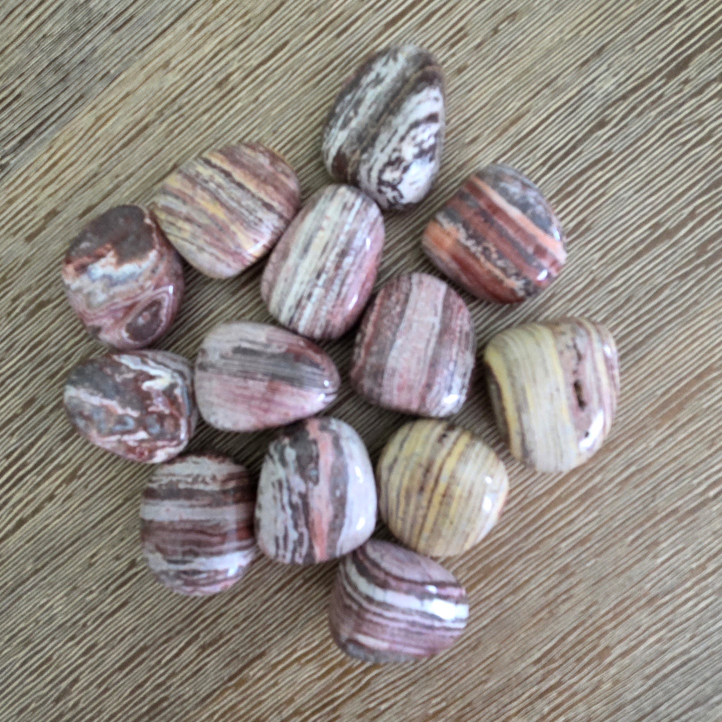 Polished stone beads with striped patterns on a wooden surface