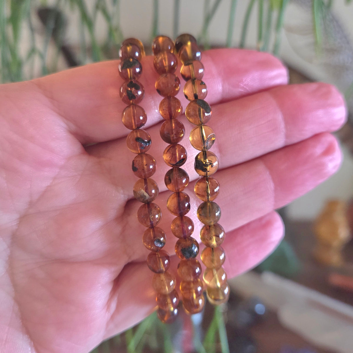 Hand holding a set of amber-colored beaded bracelets with a blurred background