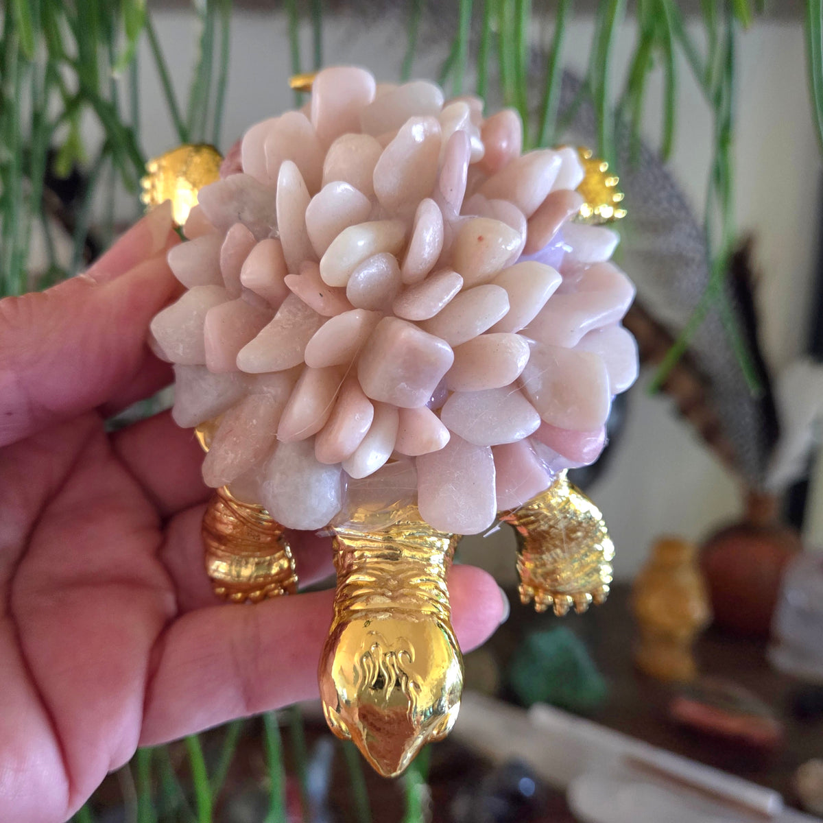 Decorative object resembling a flower made of stones with gold accents held by a hand.