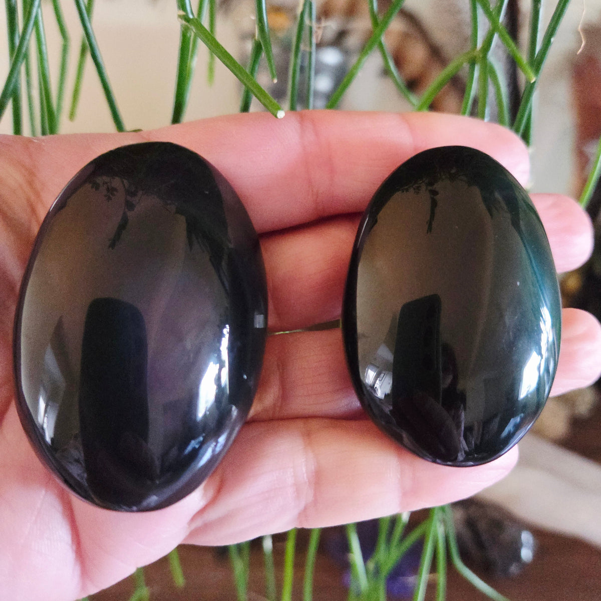 Two black stones held in a hand with a blurred background