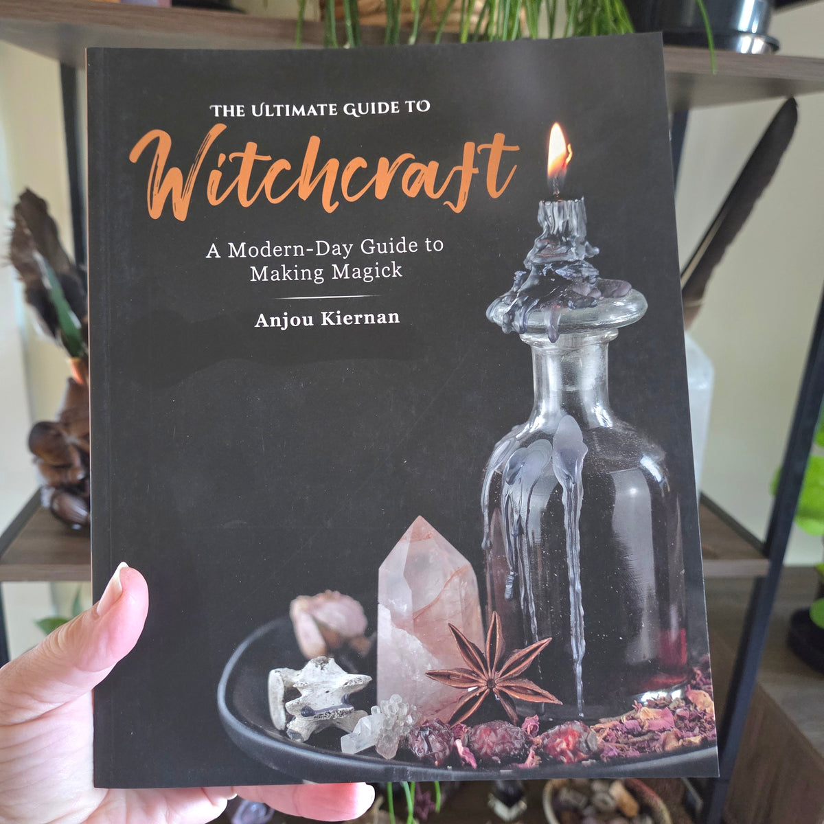 Book titled 'The Ultimate Guide to Witchcraft' held by a person