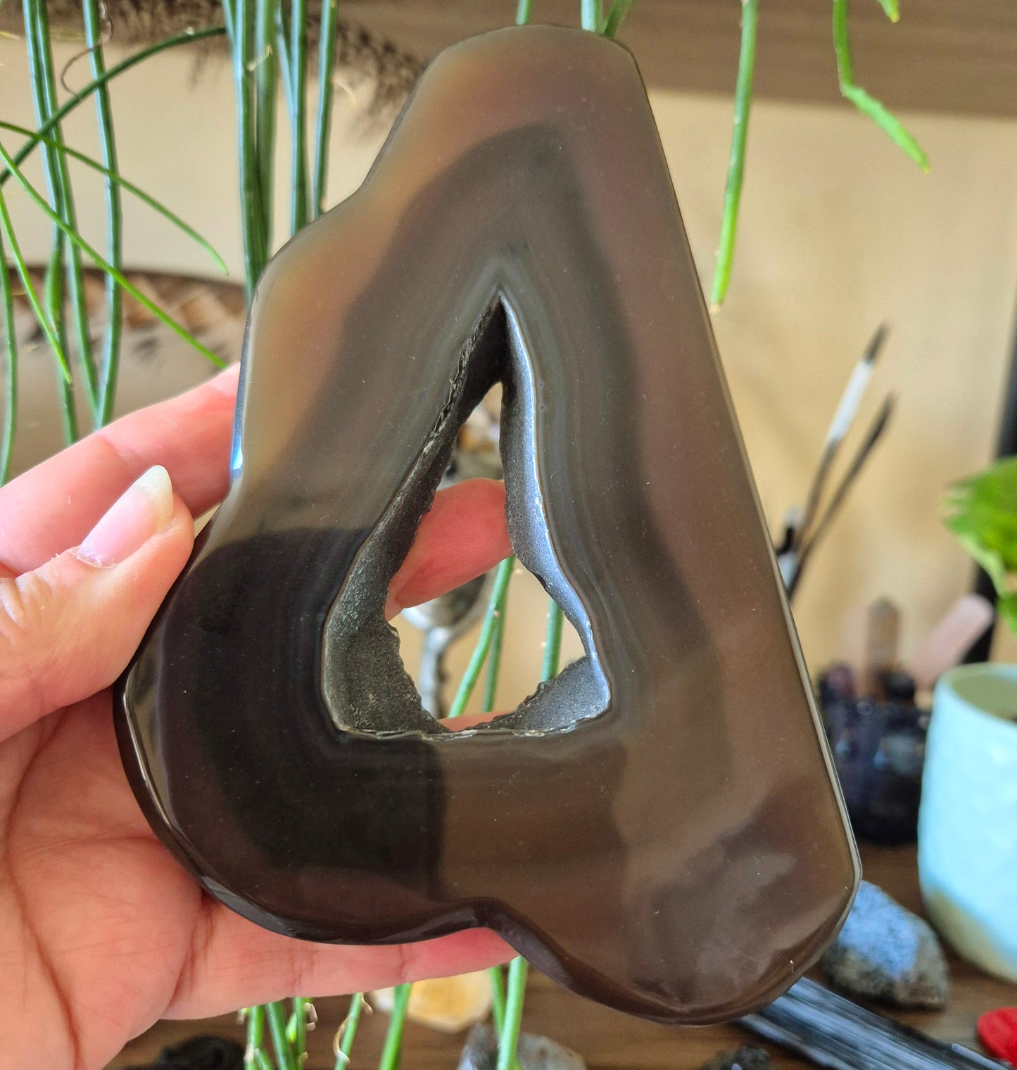 A polished agate gemstone in the shape of a cloud with a single pointed extension, held in a person's hand.