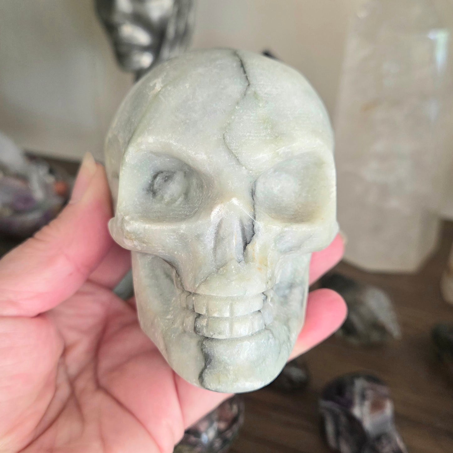 Hand holding a stone skull sculpture with a blurred background
