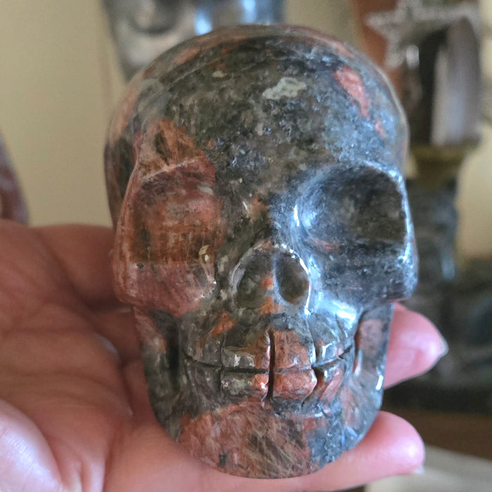 Rock crystal skull held in a hand with a blurred background