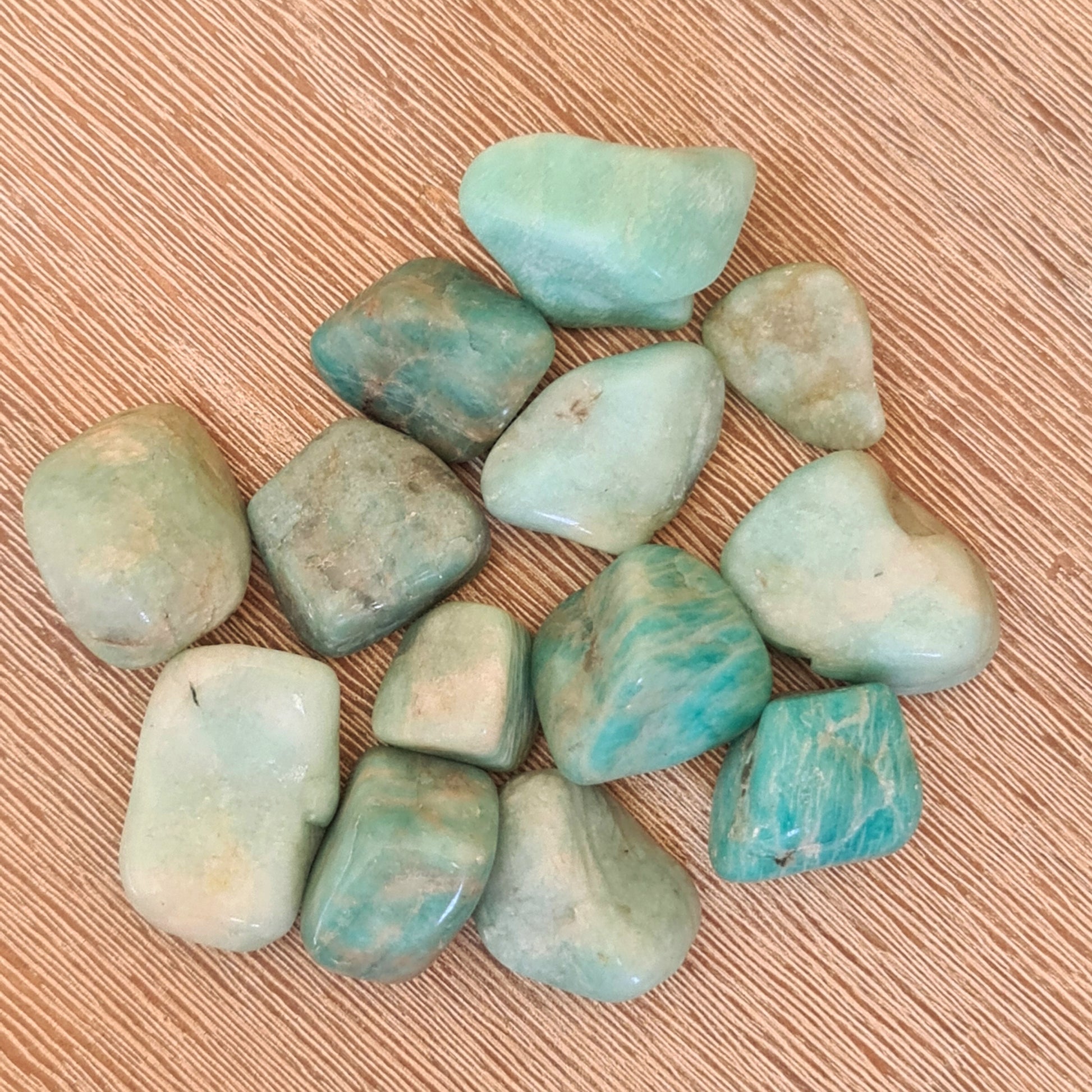 A collection of polished Amazonite stones displayed on a wooden surface.