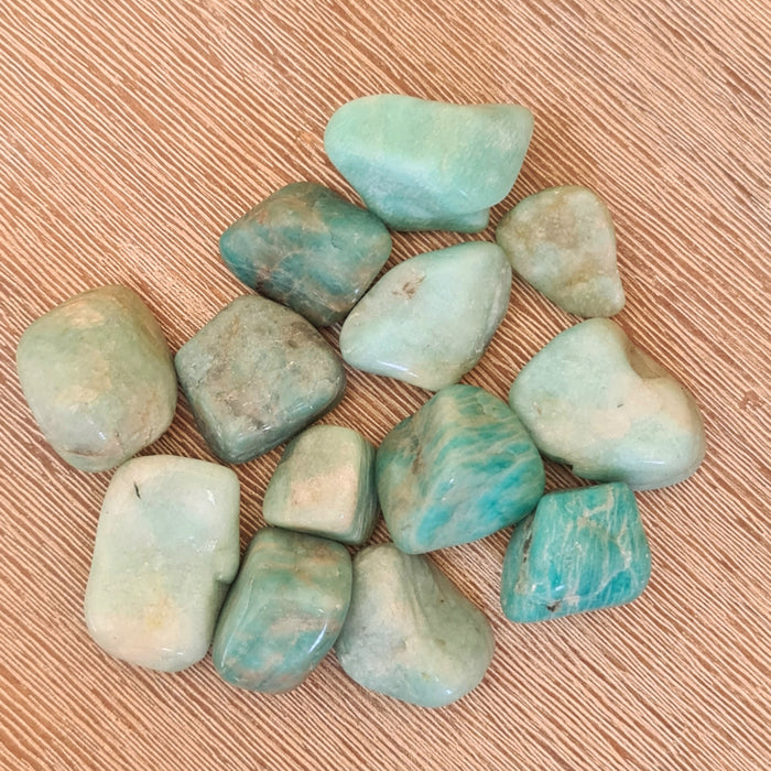 A collection of polished Amazonite stones displayed on a wooden surface.
