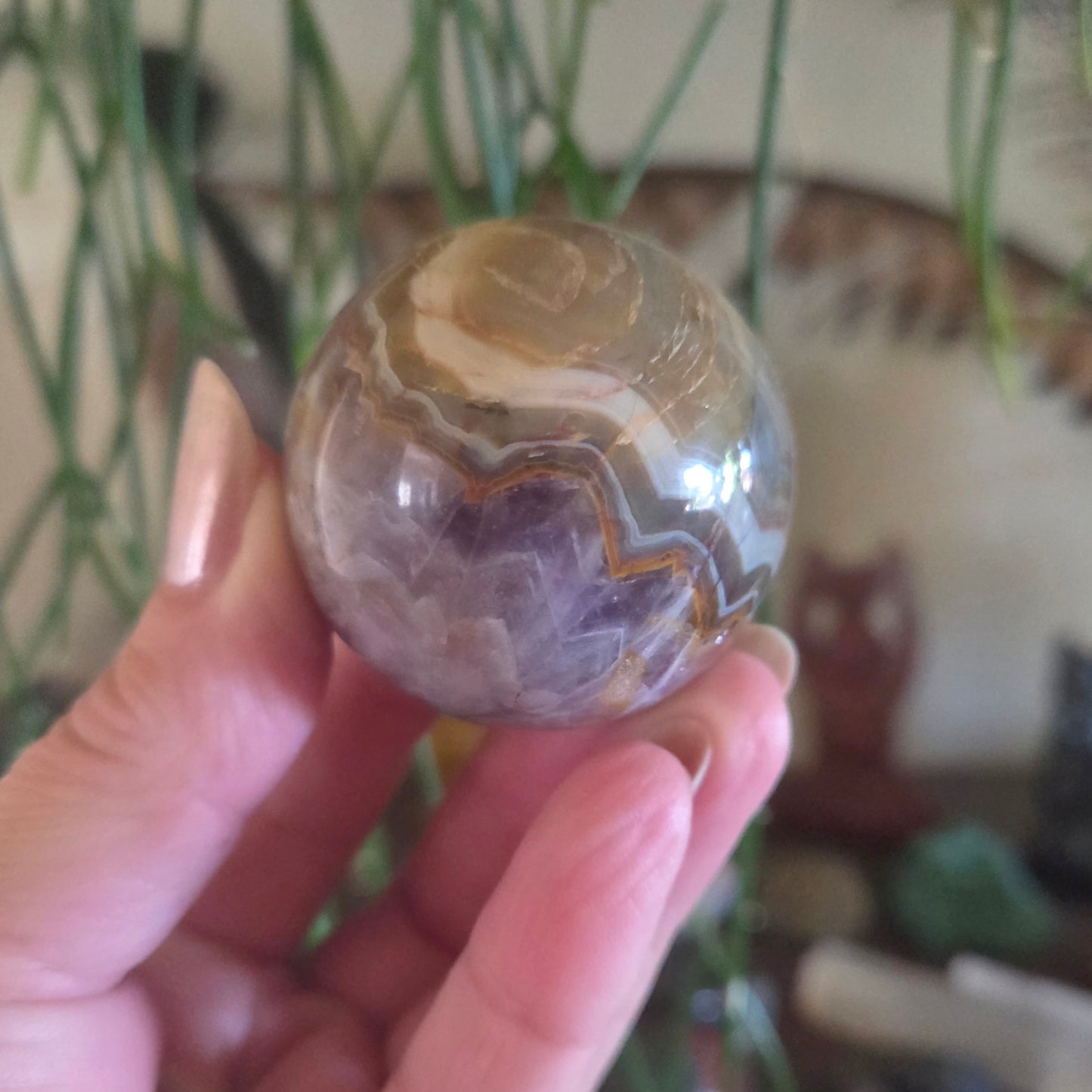 Hand holding a marbled stone sphere with a blurred indoor background