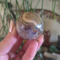 Hand holding a marbled stone sphere with a blurred indoor background