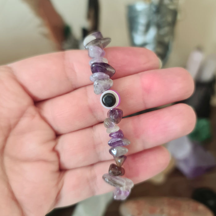 A multicolored beaded bracelet, featuring a variety of geometric shaped beads, held in a person's hand.