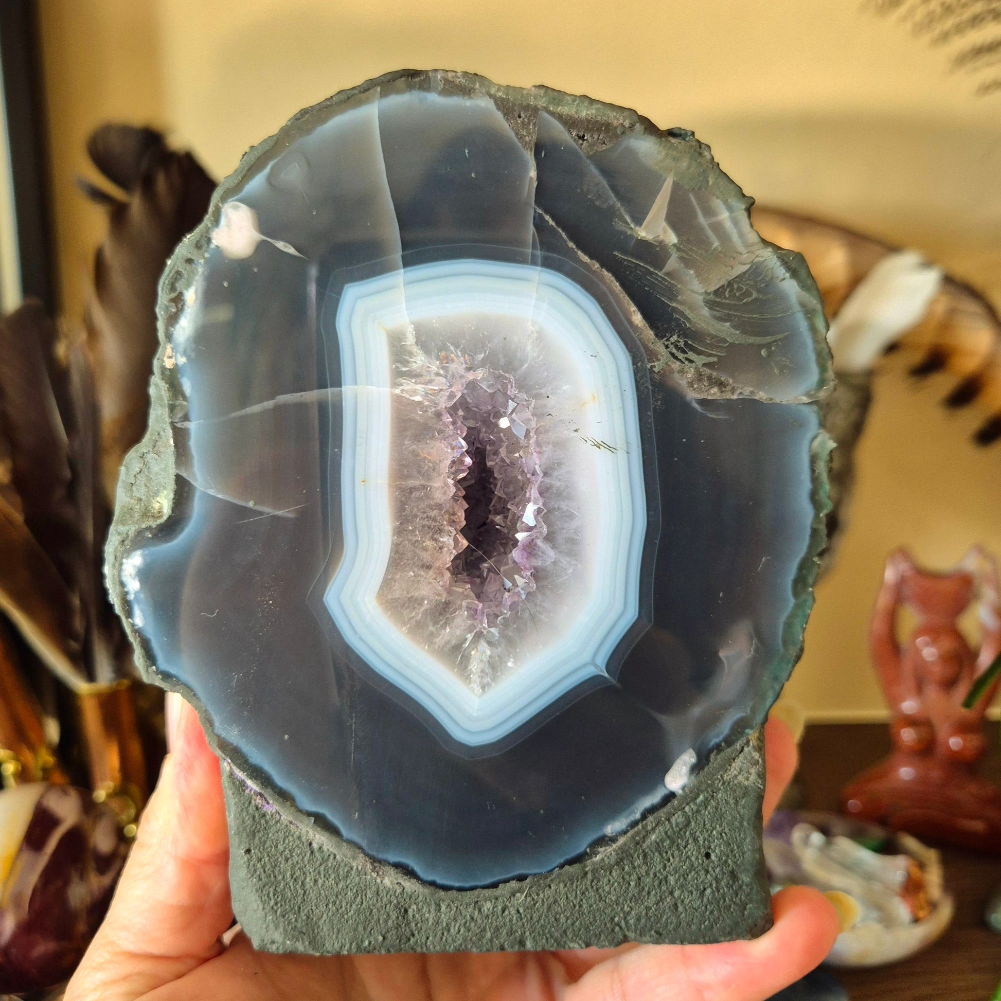 A person holding a polished amethyst geode with a visible purple and white crystal inside.