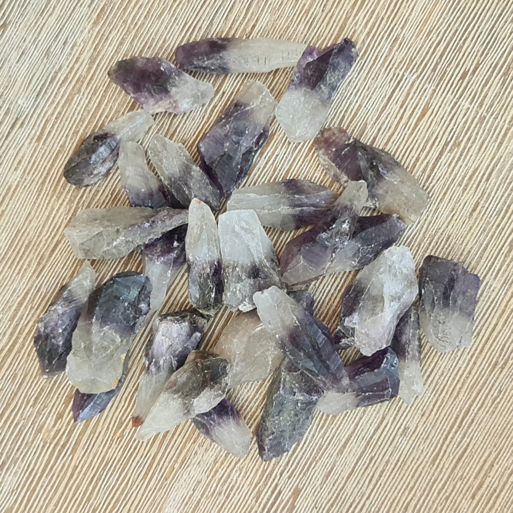 A collection of polished purple amethyst points on a wooden surface.
