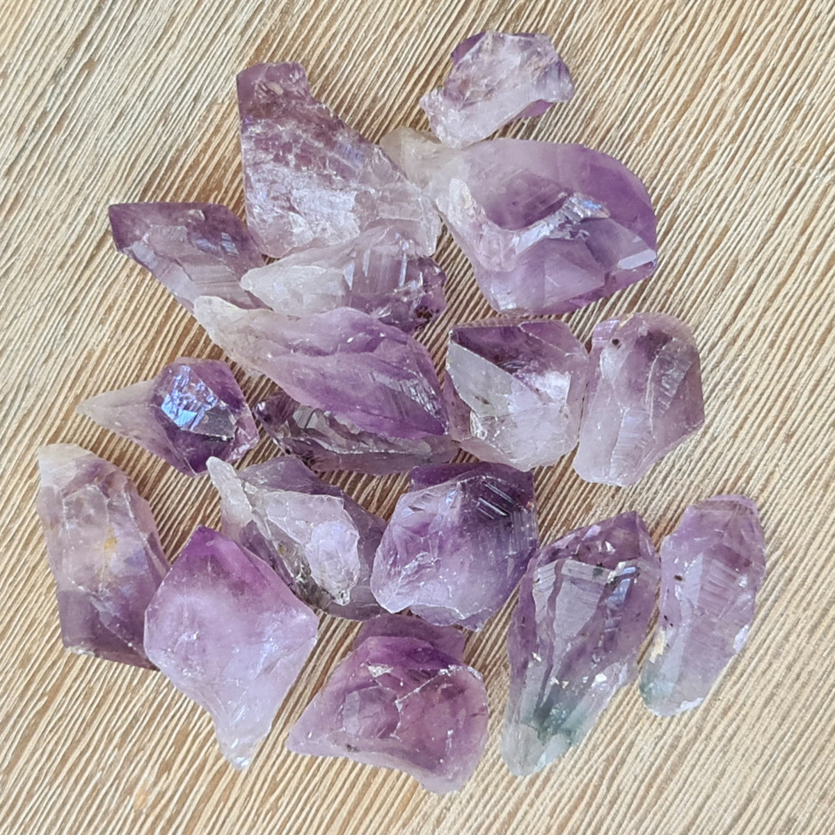 A collection of raw amethyst crystal points displaying varying shades of purple and violet.