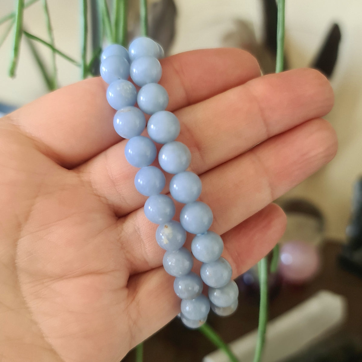 A hand holding a blue crystal bracelet with a solid pattern.