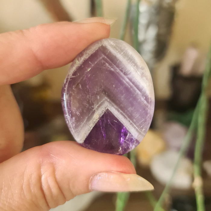 Chevron amethyst oval crystal held in a hand