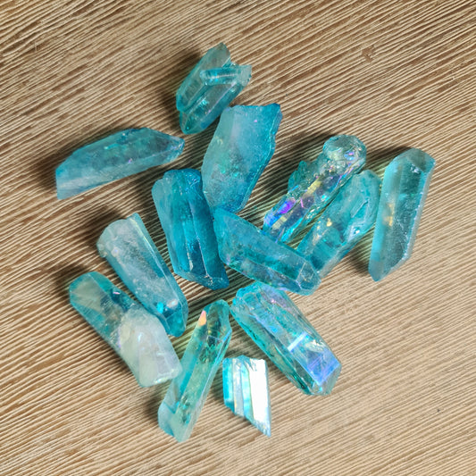 A collection of polished blue Aqua Aura quartz crystal points on a wooden surface.