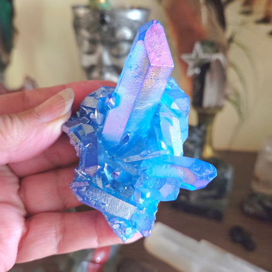 Blue and purple crystal held in a hand with a blurred background