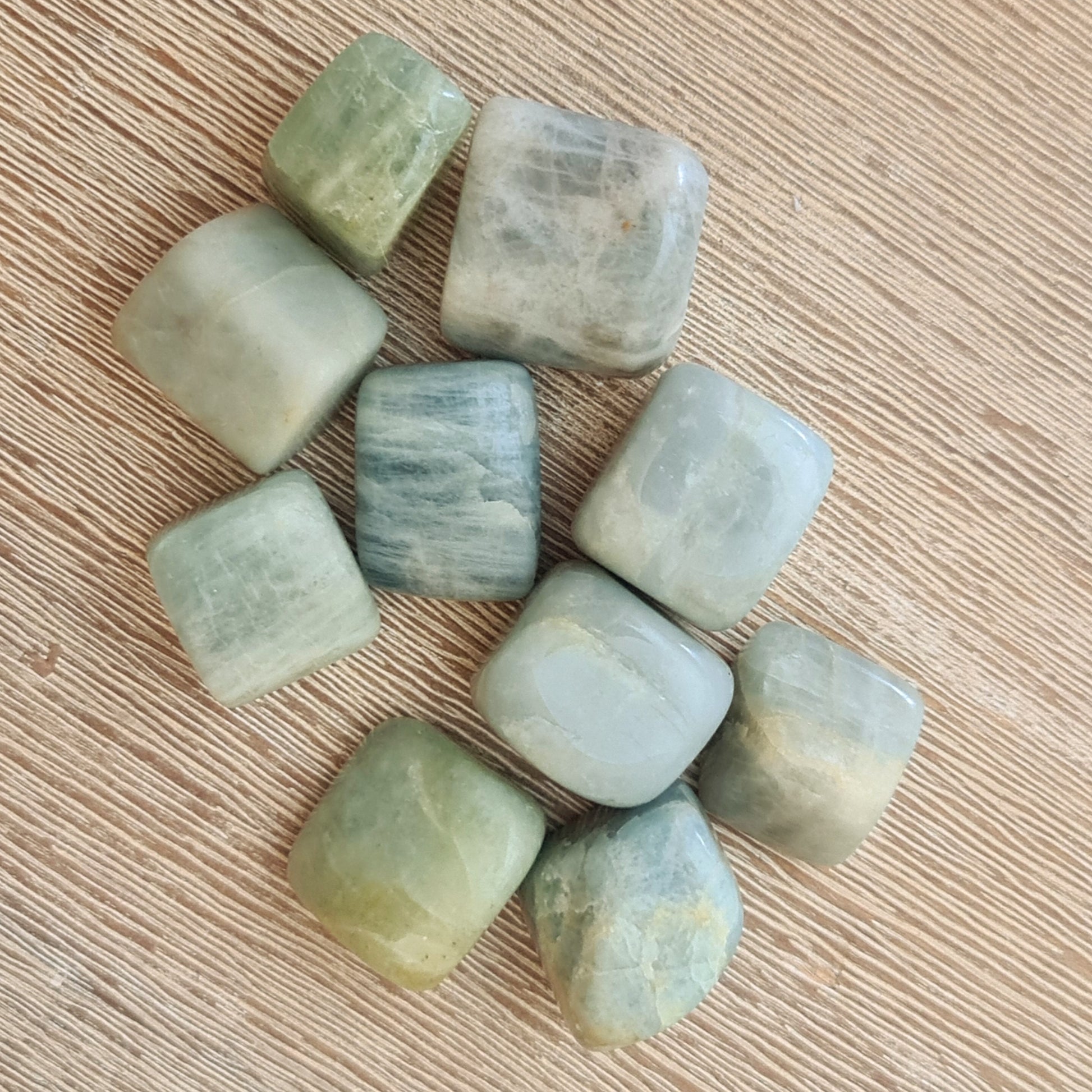 A collection of polished aquamarine cubes arranged on a wooden surface.