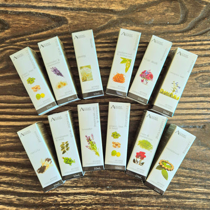 A collection of Aroma Concentrate Oil bottles displayed in a fan-like arrangement on a wooden surface. Each bottle has a label with a different floral or botanical design.