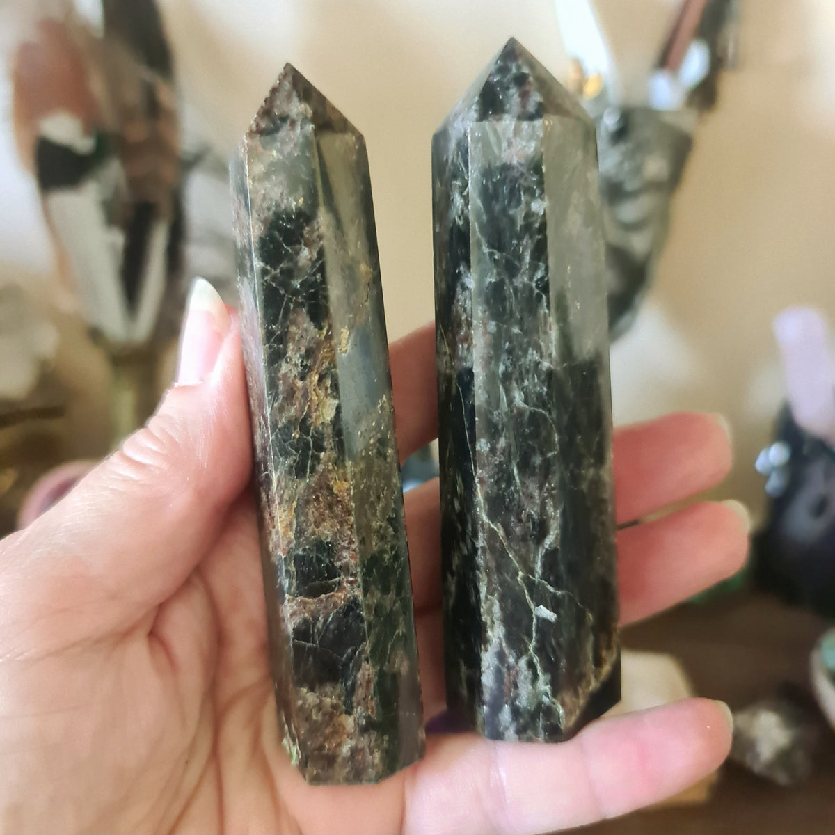 Two polished, marble-like crystal stones held in a person's hand, with a blurred background suggesting they are the main focus.