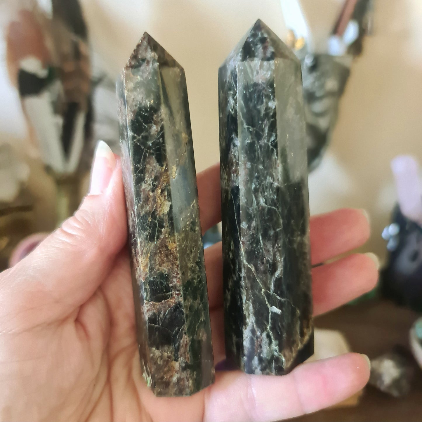 Two polished, marble-like crystal stones held in a person's hand, with a blurred background suggesting they are the main focus.