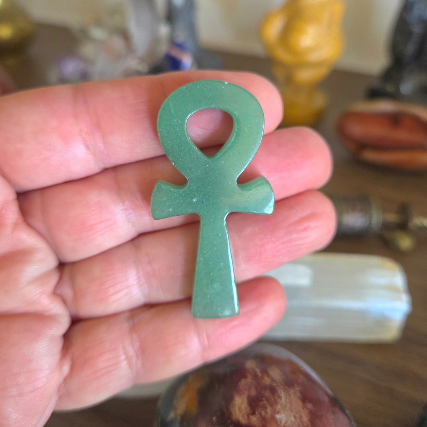 Hand holding a green ankh symbol against a blurred background