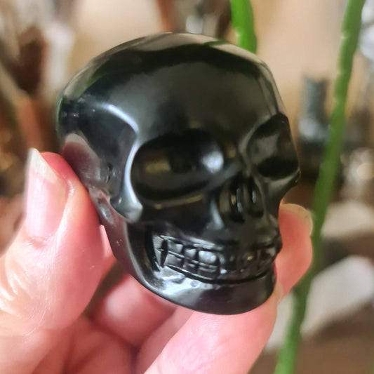 A small black obsidian skull figurine held in a person's hand.