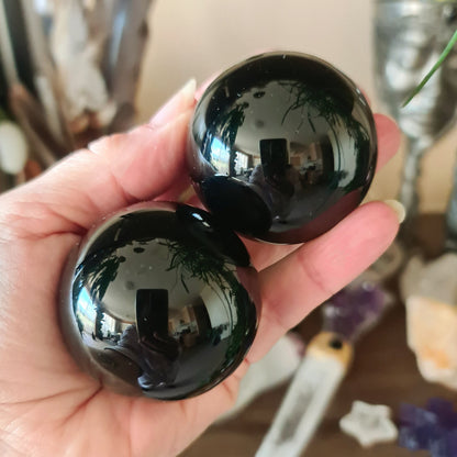 A person holding a medium-sized black obsidian sphere.