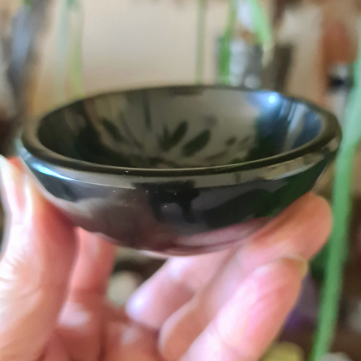 A hand holding a Black Onyx bowl with a smooth, glossy finish.