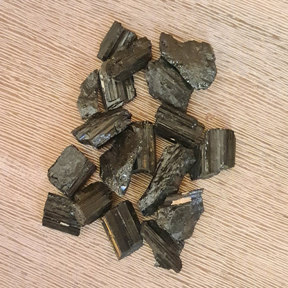 A collection of polished Black Tourmaline stones of various shades displayed on a wooden surface.