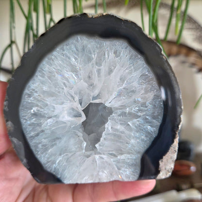 Close-up of a crystal geode held in hand with a blurred natural background