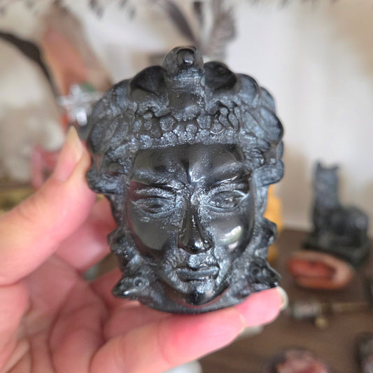Black decorative head sculpture held in a hand with a blurred background
