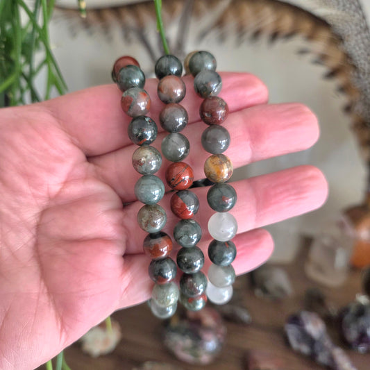 Hand holding a set of multicolored beaded bracelets with a blurred background