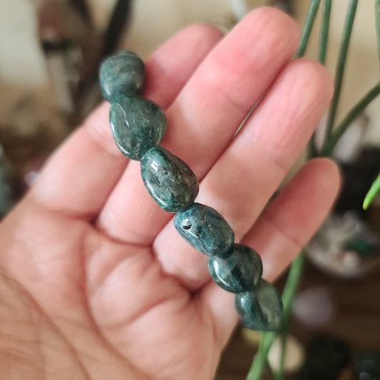 A hand holding a blue Apatite bracelet with a chunky style on elastic.