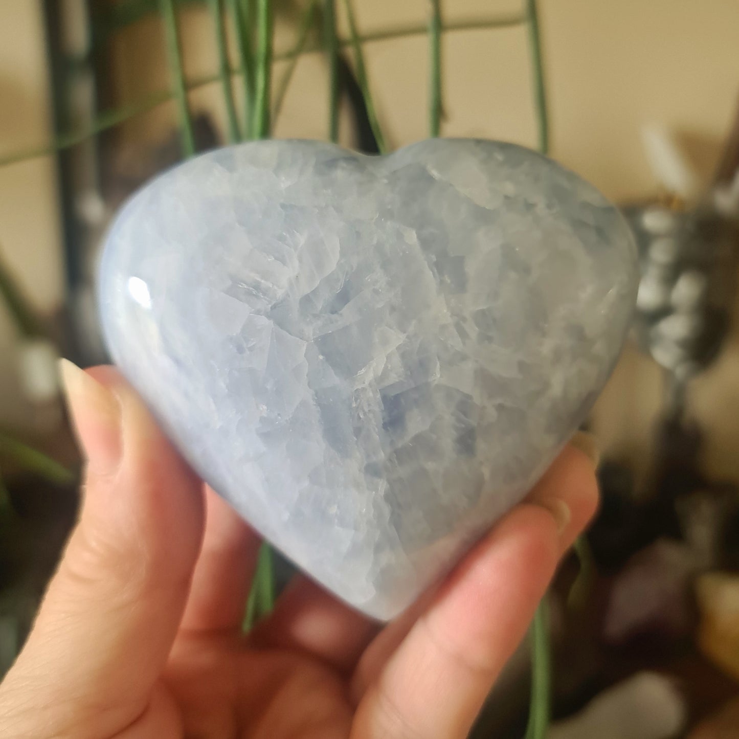 A person holding a large blue calcite heart-shaped stone