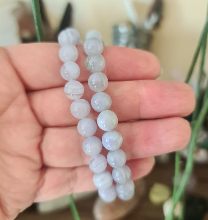 A person holding a bracelet with blue lace agate beads.