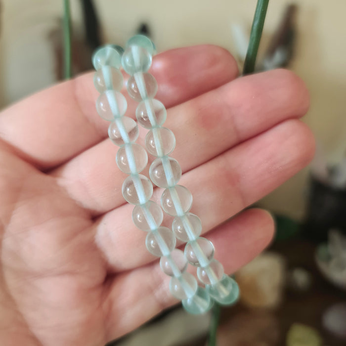 A bracelet made of blue obsidian stones connected with a silver-colored bead chain.