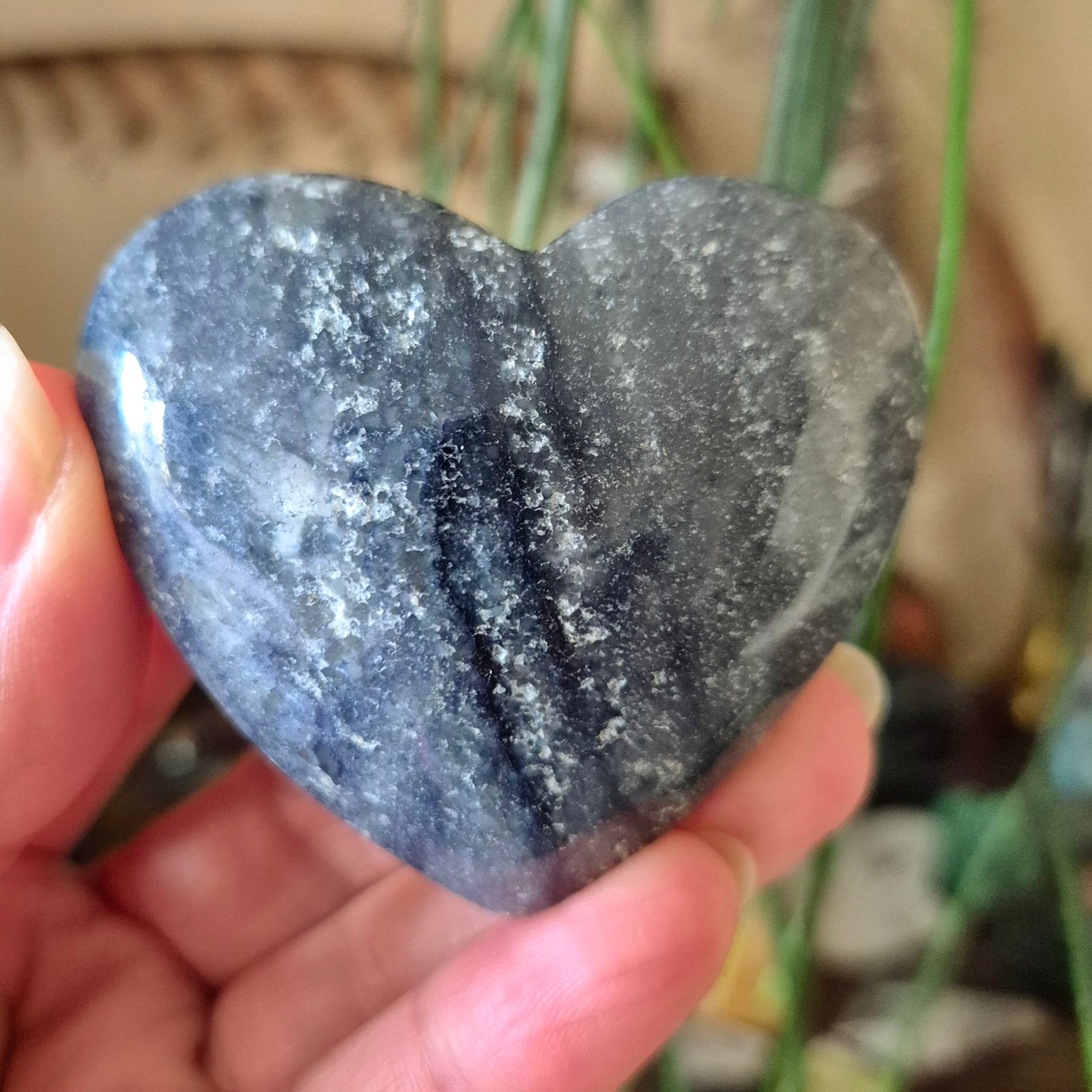 A heart-shaped blue quartz stone being held by a person.